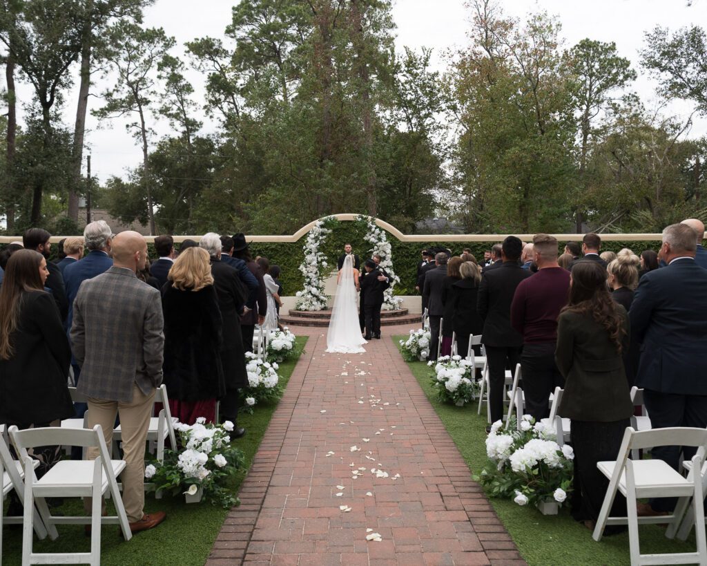 Outdoor wedding ceremony setup at The Springs Cypress with white chairs, floral aisle decor, and ceremony arch