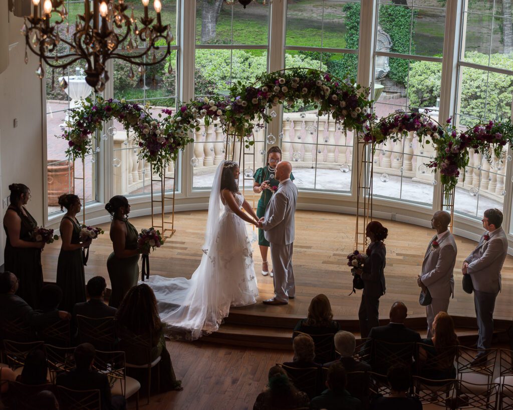 Wide view of indoor wedding ceremony setup at The Springs Cypress with floral arch and guest seating