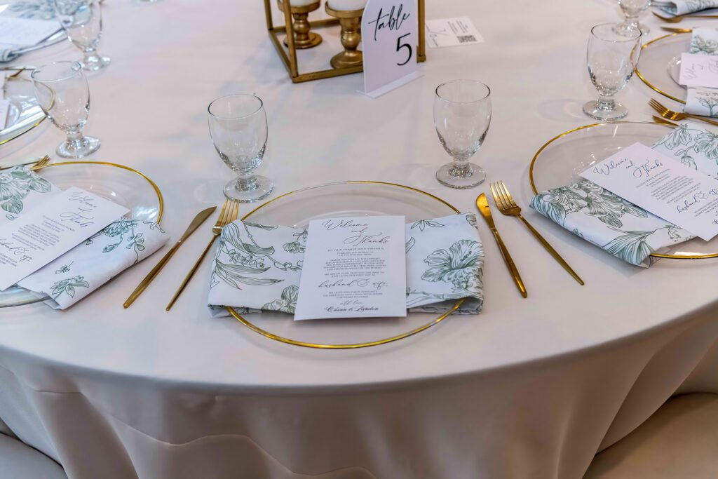 Elegant wedding table place setting at The Springs Cypress with white charger, floral napkin, and glassware